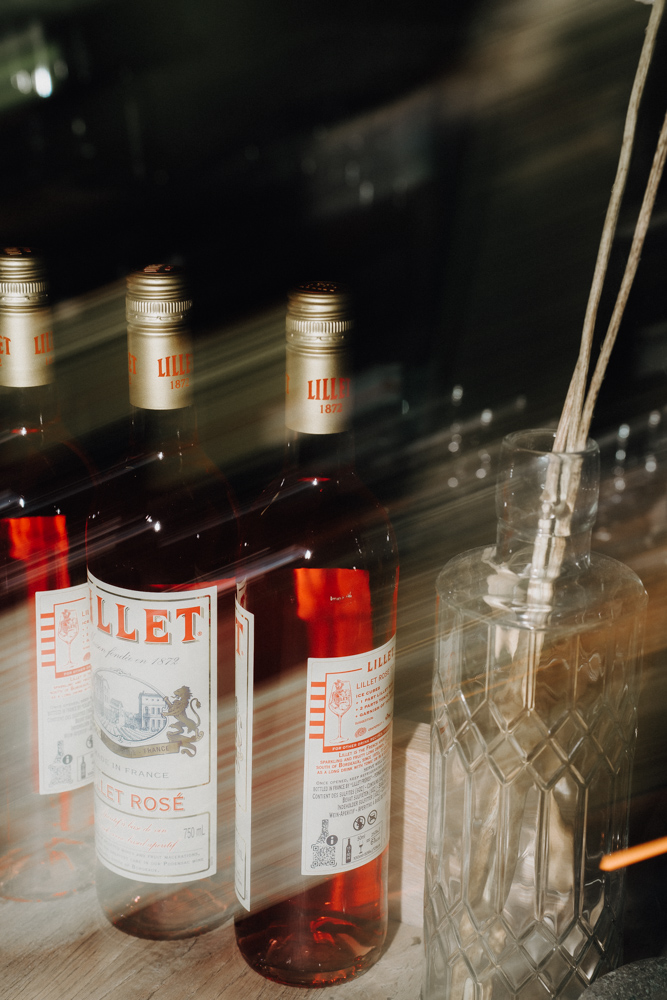 Stilvoll arrangierte Flaschen Lillet Rosé als Detailaufnahme bei der Hochzeit in der Deantnerin