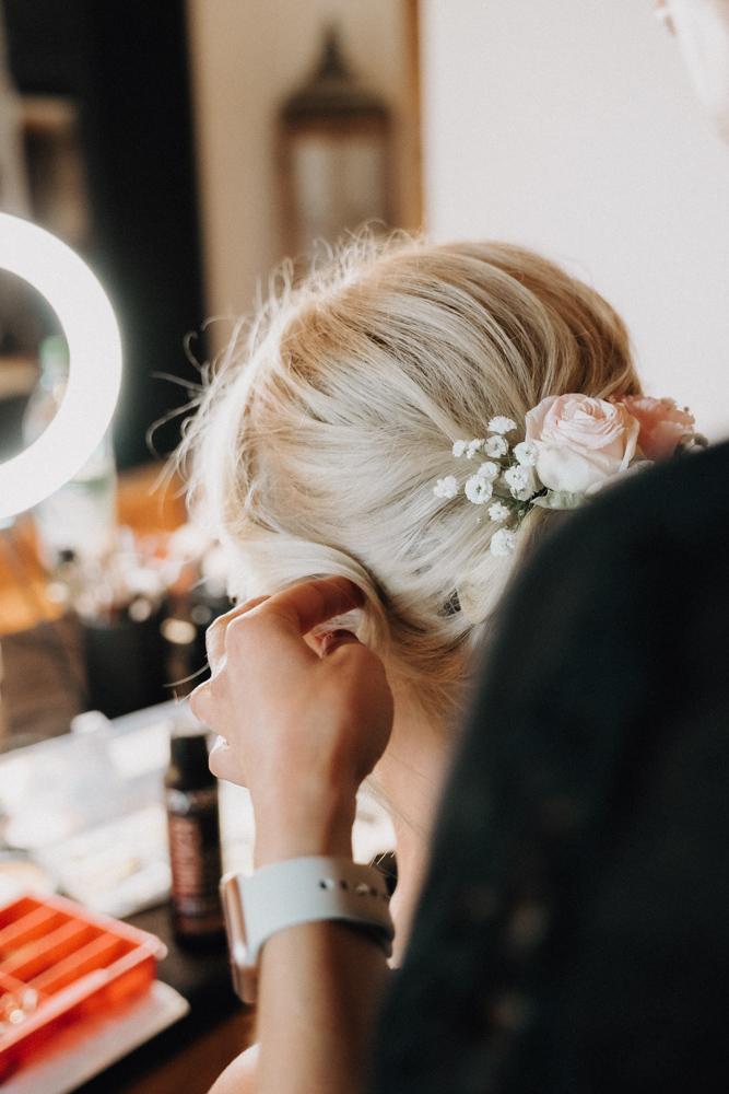 Getting Ready der Braut bei der Hochzeit im Pitzlloch – Detailaufnahme der Hochsteckfrisur mit Blumen.