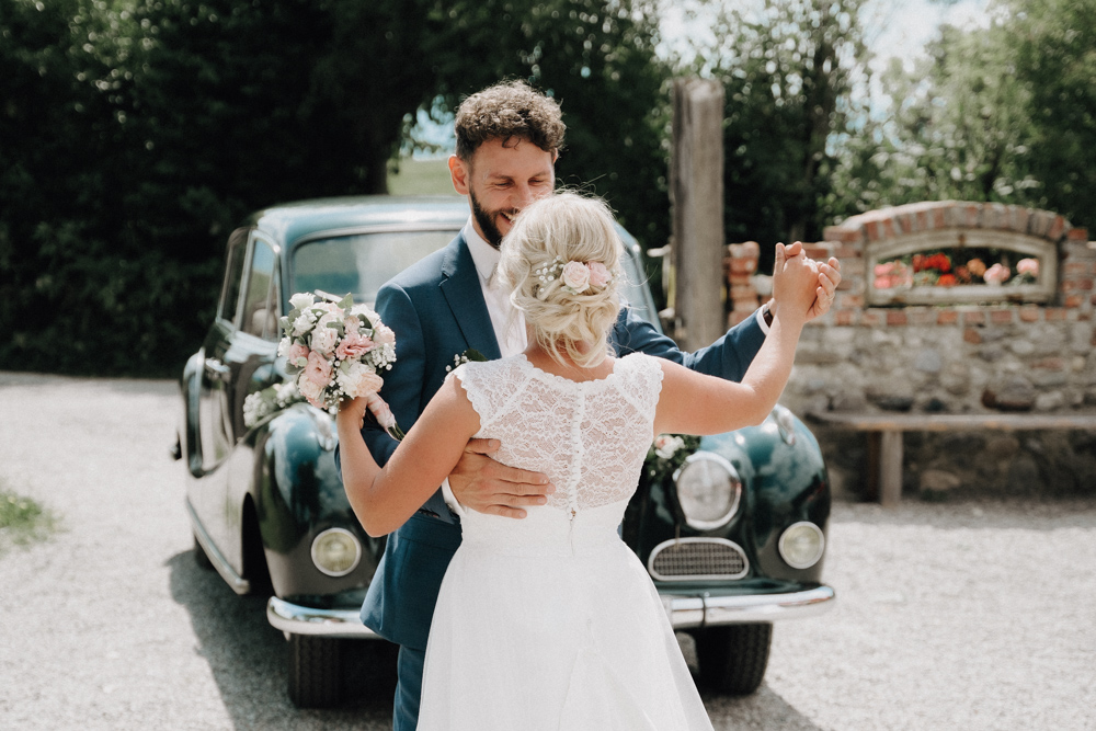 Brautpaar tanzt vor einem Oldtimer – Romantische Momente bei der Hochzeit im Pitzlloch.