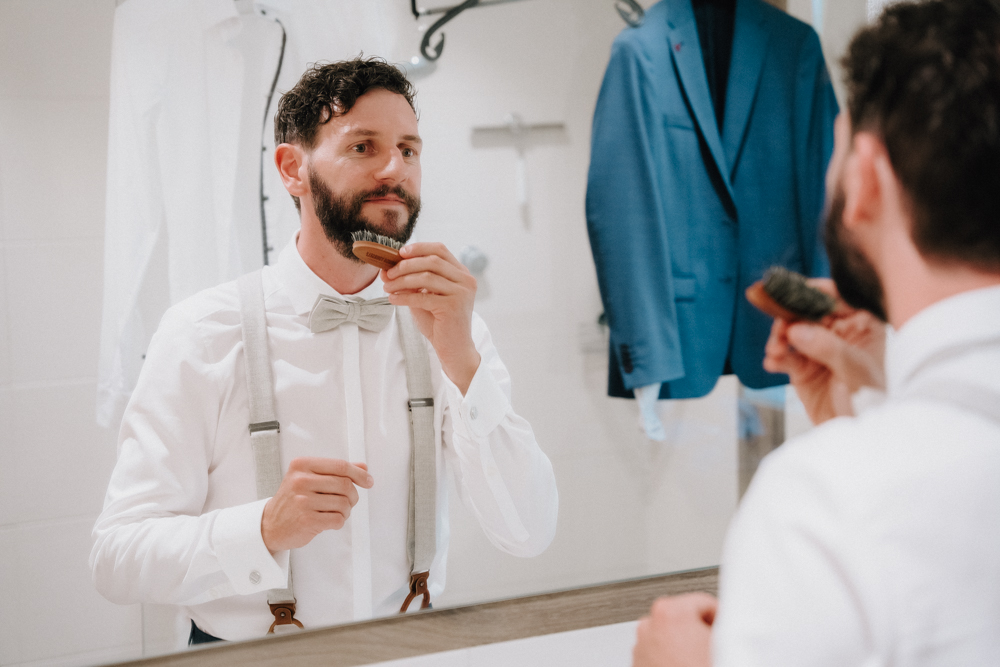 Bräutigam stylt sich vor der Hochzeit im Pitzlloch – Vorbereitung mit Fliege und Bartbürste.