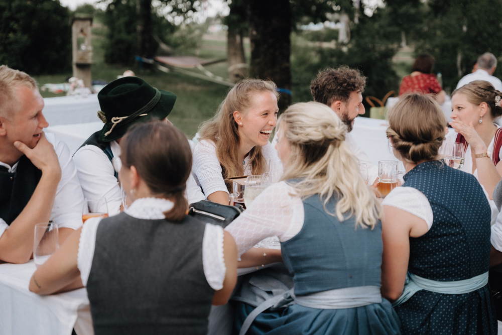 Gäste in Tracht genießen die Hochzeit im Pitzlloch – Fröhliche Stimmung im Garten.