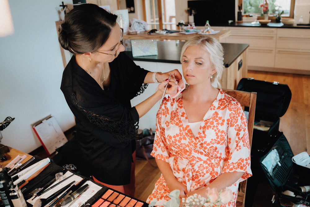 Braut bekommt das Make-up für die Hochzeit im Pitzlloch – Vorbereitung in entspannter Atmosphäre.